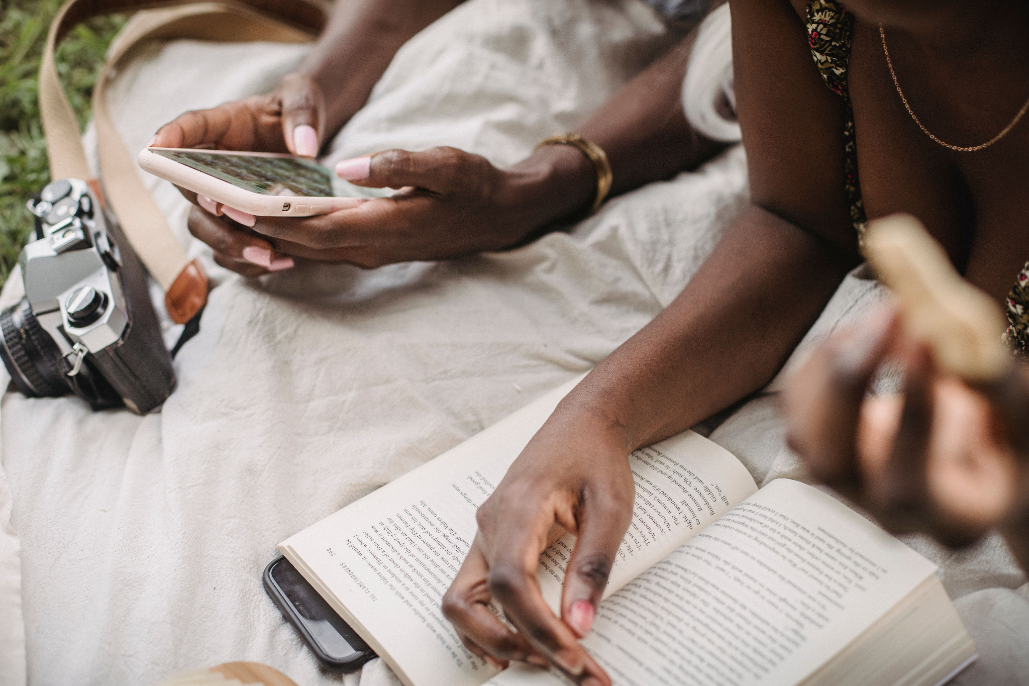 Hands using a smartphone beside an open book